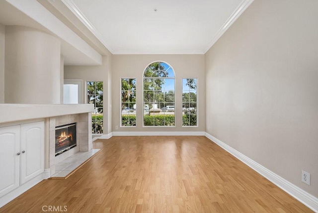 unfurnished living room featuring ornamental molding, a fireplace, light wood-style flooring, and baseboards