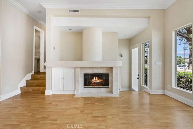 unfurnished living room with light wood finished floors, baseboards, visible vents, and ornamental molding