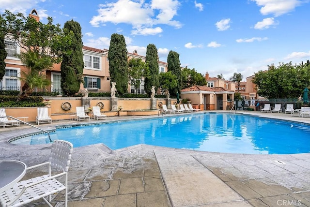 pool with a residential view, fence, and a patio