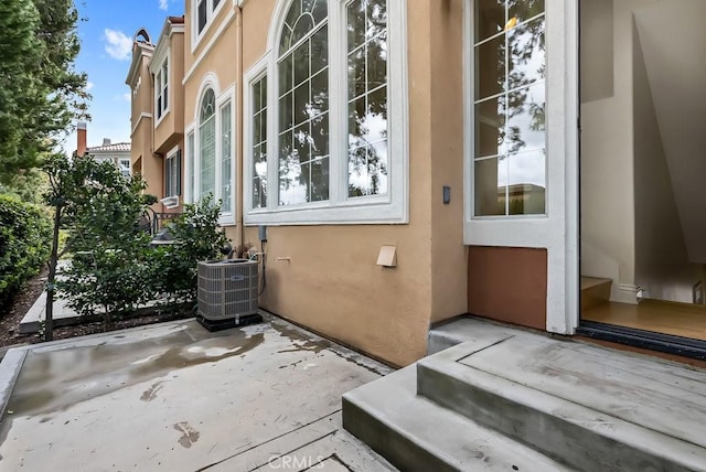 exterior space with a patio, cooling unit, and stucco siding