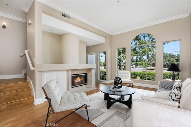 living room with visible vents, stairway, light wood-style floors, ornamental molding, and baseboards