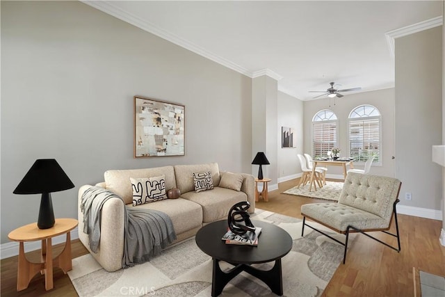 living room featuring ornamental molding, ceiling fan, baseboards, and wood finished floors