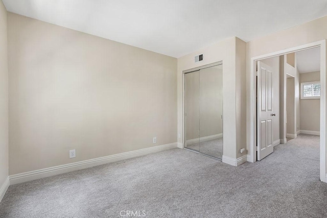 unfurnished bedroom with carpet, a closet, visible vents, and baseboards