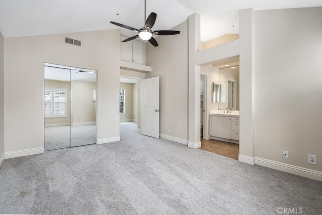 unfurnished bedroom with visible vents, baseboards, carpet, high vaulted ceiling, and a closet