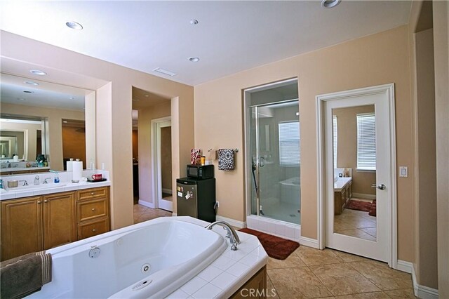 full bath with a shower stall, vanity, tile patterned flooring, a whirlpool tub, and baseboards