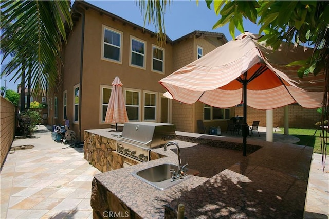 view of patio / terrace with exterior kitchen, a fenced backyard, a sink, and grilling area