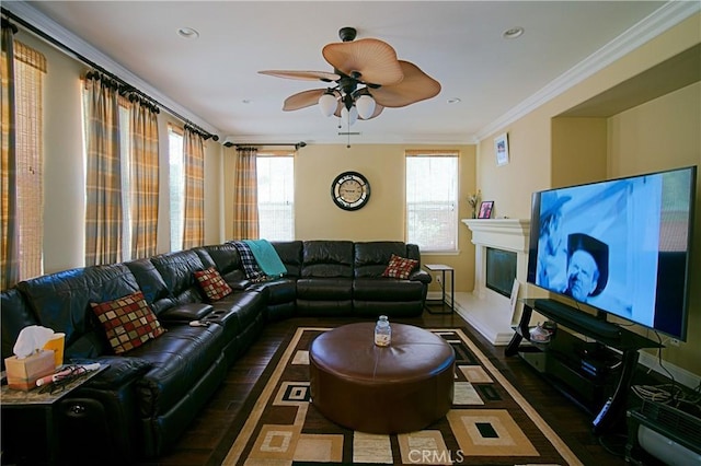 living room featuring baseboards, a glass covered fireplace, a wealth of natural light, and crown molding