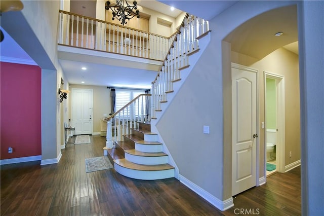 stairs with wood-type flooring, arched walkways, and baseboards