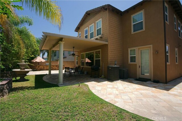 back of property featuring cooling unit, fence, a ceiling fan, a yard, and a patio area