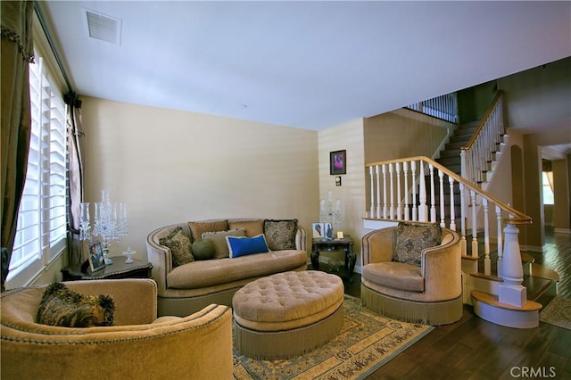 living area featuring plenty of natural light, stairs, visible vents, and wood finished floors