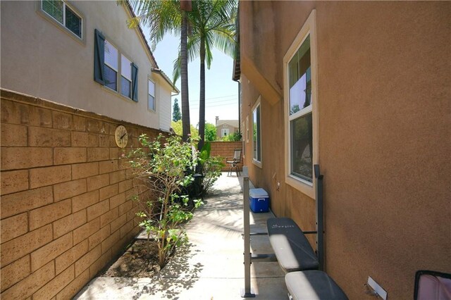 view of side of home featuring a patio area, fence, and stucco siding