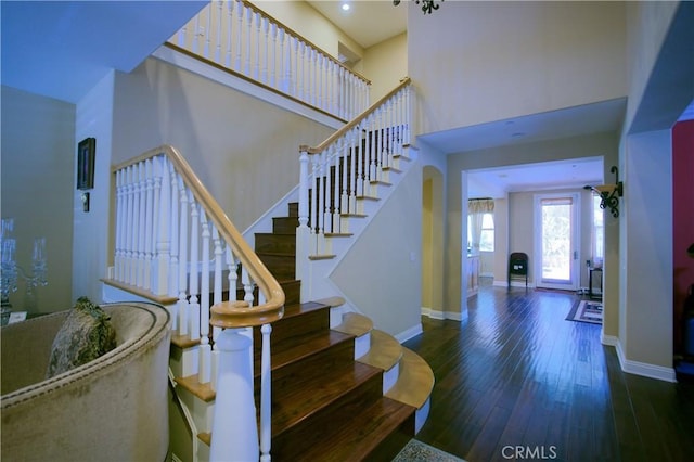 staircase with baseboards, a towering ceiling, and hardwood / wood-style floors