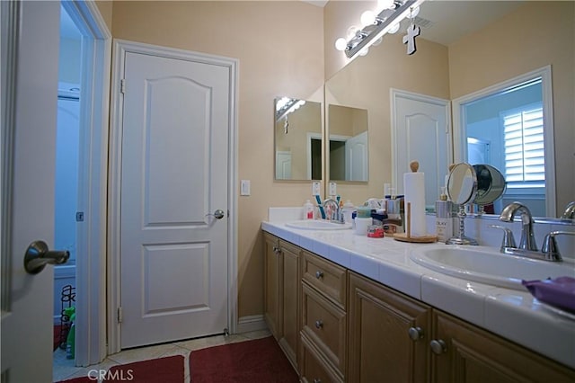 bathroom featuring double vanity, a sink, and tile patterned floors