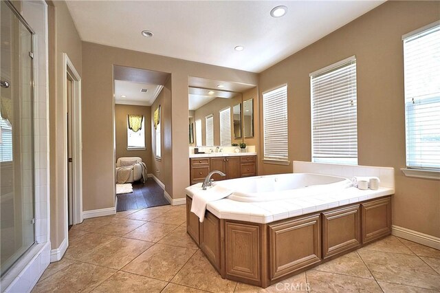 bathroom featuring a bath, a stall shower, tile patterned flooring, and vanity