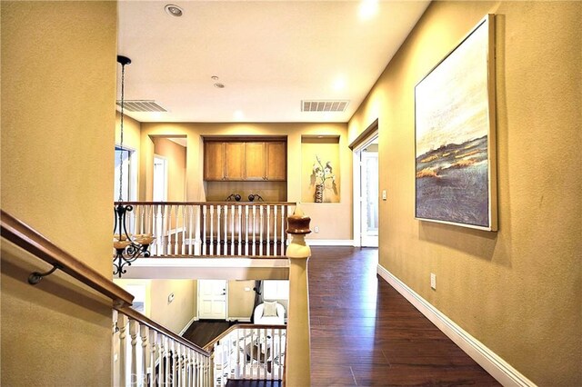 hall featuring dark wood-style floors, baseboards, and visible vents