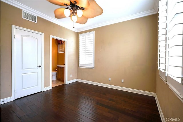 unfurnished bedroom featuring dark wood-style flooring, visible vents, crown molding, baseboards, and connected bathroom