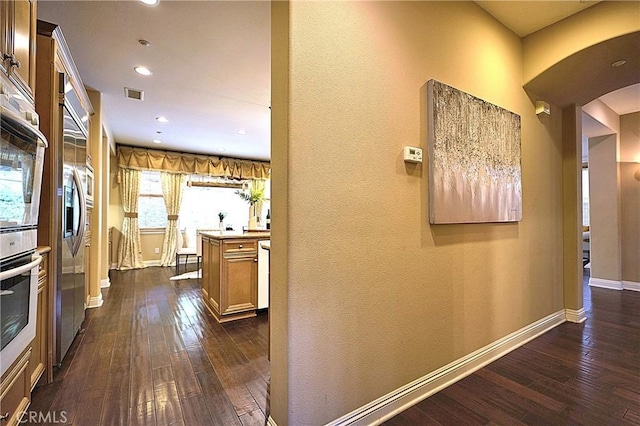 hall with dark wood finished floors, baseboards, visible vents, arched walkways, and recessed lighting