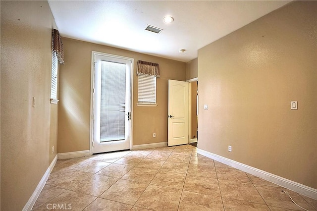 spare room with light tile patterned floors, baseboards, and visible vents