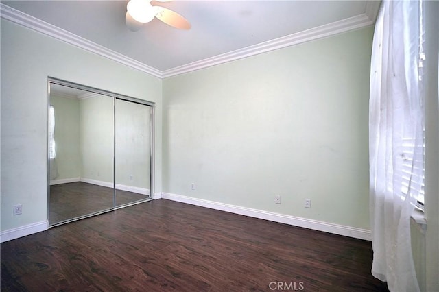 unfurnished bedroom featuring baseboards, ornamental molding, wood finished floors, and a closet