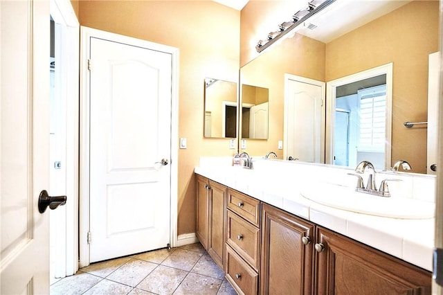 bathroom with tile patterned flooring, a sink, double vanity, and baseboards