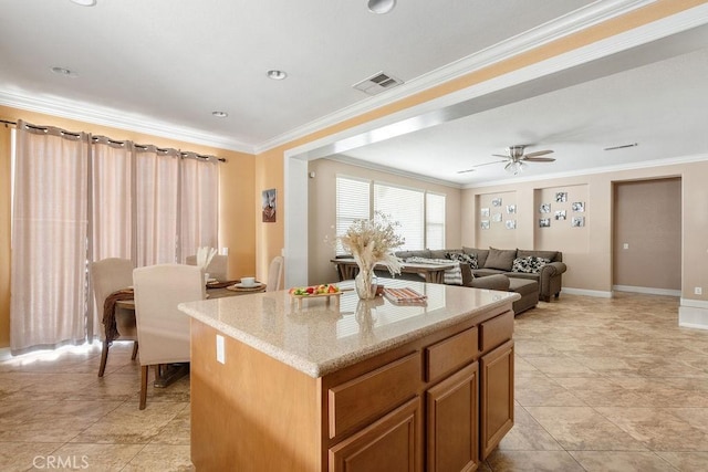 kitchen featuring visible vents, ornamental molding, a center island, brown cabinetry, and light stone countertops