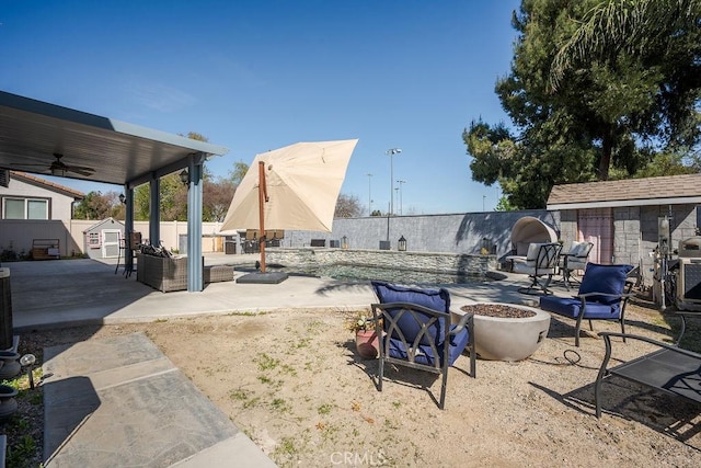 view of yard with a patio, a ceiling fan, a fenced backyard, an outdoor structure, and a fire pit