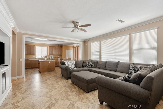 living area featuring visible vents, crown molding, and a ceiling fan