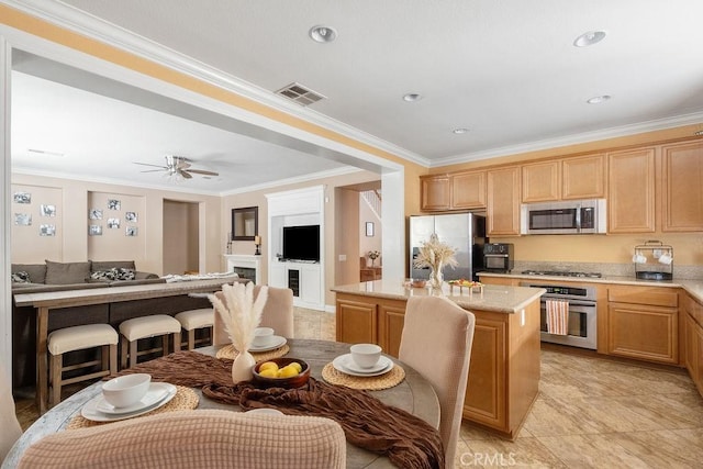 kitchen featuring visible vents, a center island, open floor plan, ornamental molding, and appliances with stainless steel finishes