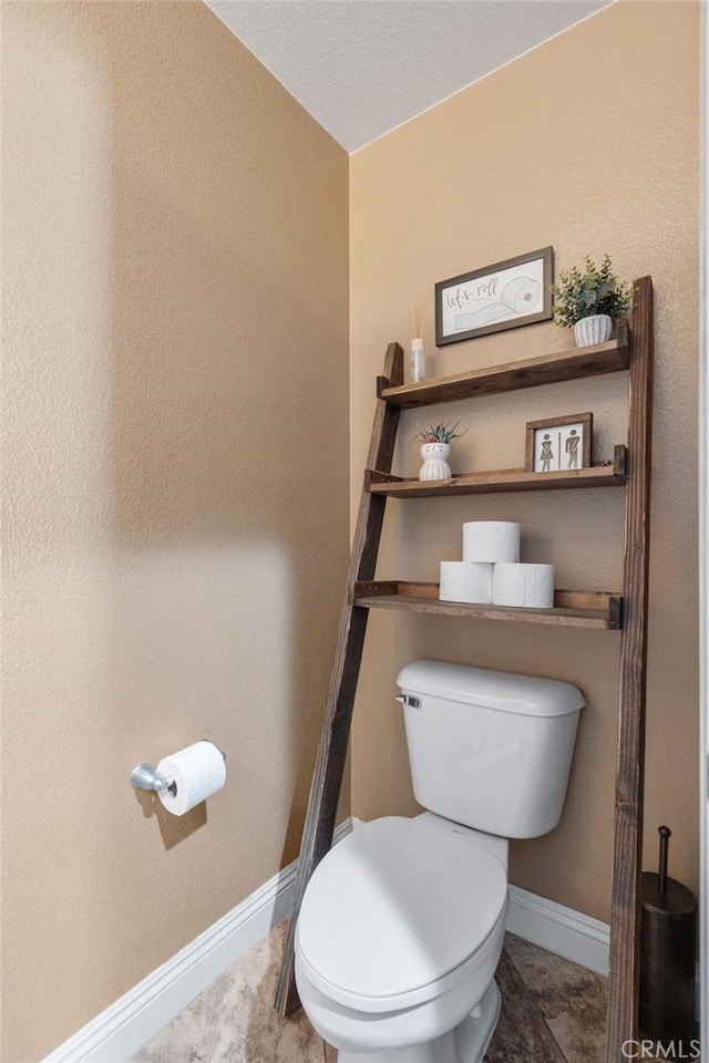 bathroom featuring baseboards and toilet