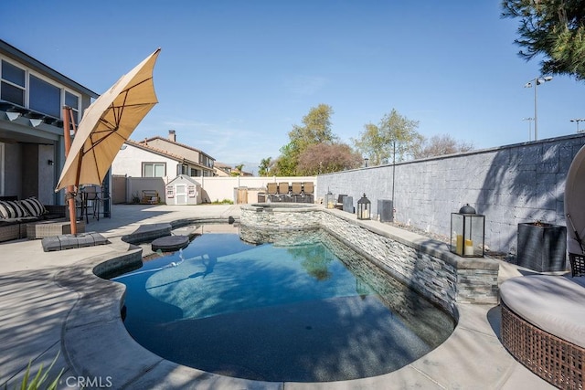 view of pool with a pool with connected hot tub, a patio, a fenced backyard, a shed, and an outdoor structure