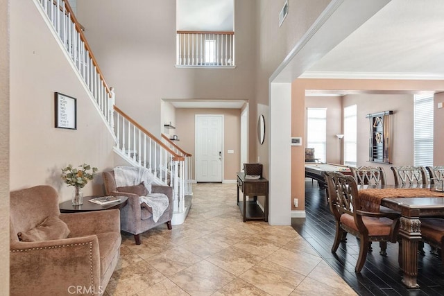 entryway featuring stairway, a healthy amount of sunlight, baseboards, and a towering ceiling