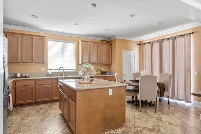 kitchen with a center island, ornamental molding, light stone counters, recessed lighting, and a sink