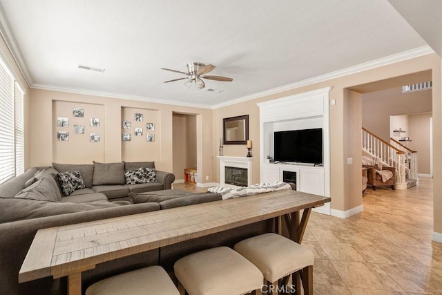 living area featuring stairs, crown molding, visible vents, and a glass covered fireplace