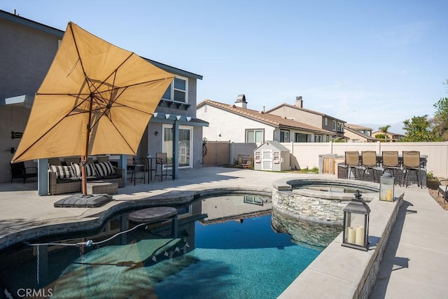 view of swimming pool with a pool with connected hot tub, an outdoor hangout area, a fenced backyard, an outbuilding, and a patio