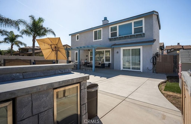 rear view of property with wine cooler, stucco siding, a patio, and a fenced backyard