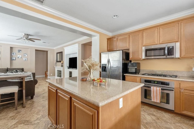 kitchen with a center island, crown molding, light stone countertops, open floor plan, and stainless steel appliances