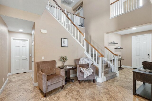 staircase featuring visible vents, baseboards, and a towering ceiling