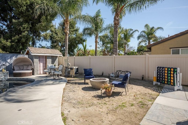 view of yard featuring an outbuilding, a patio, a fire pit, and a fenced backyard