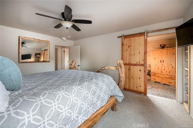 carpeted bedroom with a ceiling fan and a barn door