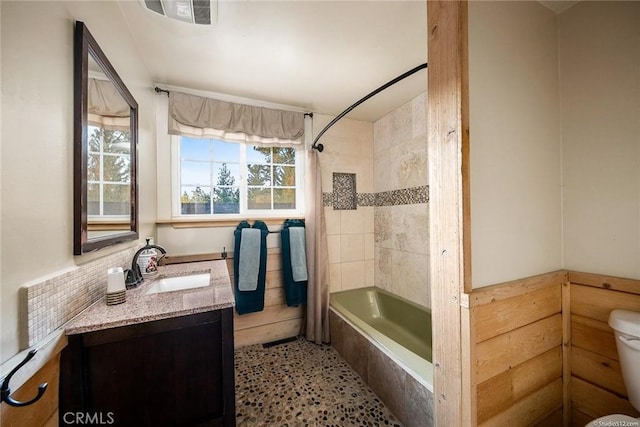 bathroom featuring toilet, visible vents, tiled shower / bath, and vanity