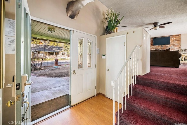 foyer featuring a textured ceiling, stairway, a ceiling fan, and light wood-style floors