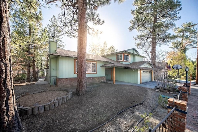 view of front of home with an attached garage, a chimney, and concrete driveway