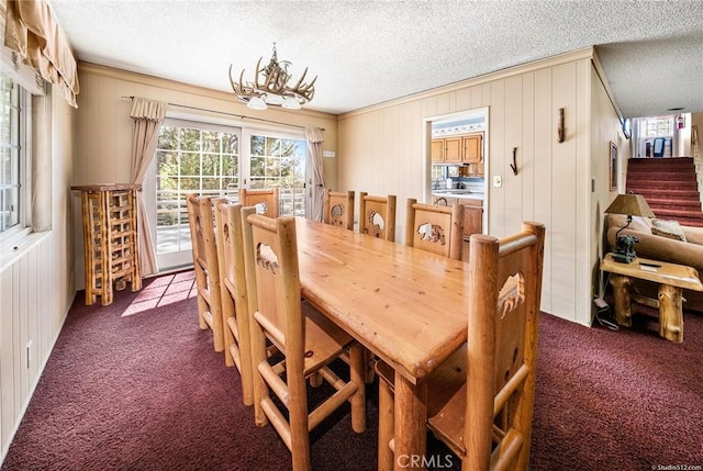 dining area featuring stairs, dark colored carpet, a textured ceiling, and an inviting chandelier