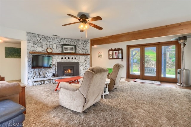 carpeted living room featuring ceiling fan, visible vents, french doors, and a stone fireplace