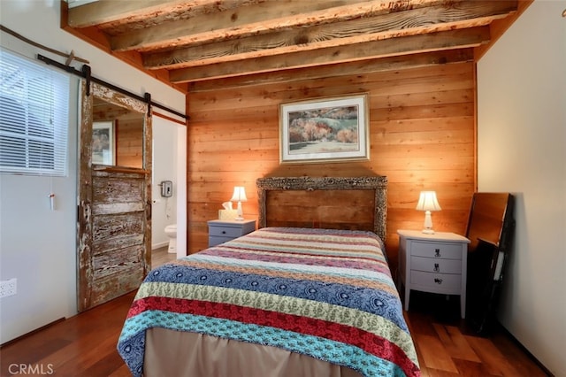 bedroom with wood walls, a barn door, wood finished floors, and beamed ceiling