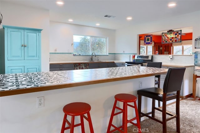 kitchen featuring a wealth of natural light, stainless steel electric range oven, visible vents, and a sink