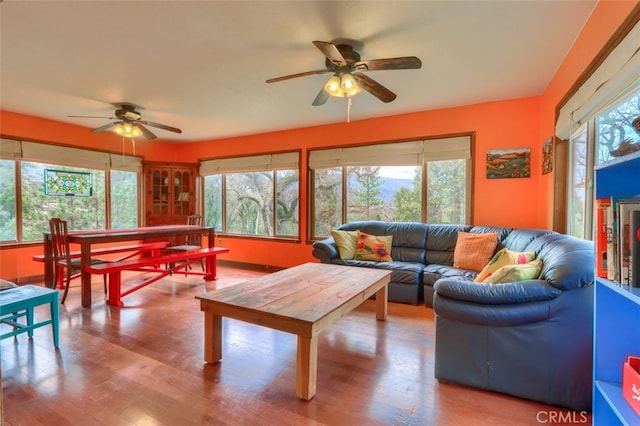 living area with a wealth of natural light, ceiling fan, and wood finished floors