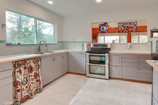 kitchen with range with two ovens, gray cabinets, a sink, and light countertops