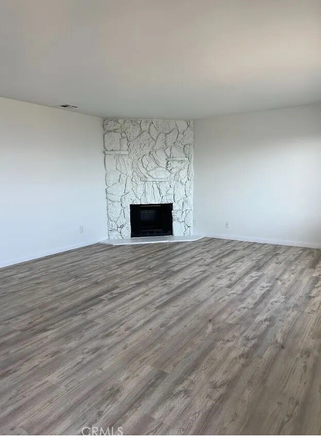 unfurnished living room featuring a fireplace, visible vents, and wood finished floors