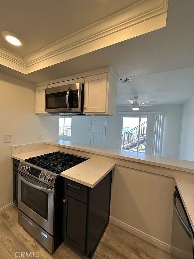 kitchen featuring visible vents, appliances with stainless steel finishes, light wood-style floors, ornamental molding, and white cabinets